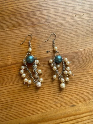 Hängande örhängen med pärlor - Mina handgjorda örhängen.  Vita pärlor på silverfärgad metalltråd.  Nickelfria!  Följ min Instagram för mer <3 @veras.smycken. Unika hängande örhängen med silvrig metalltråd och flera små vita pärlor samt en större mörkblå pärla i mitten. Örhängena har en bohemisk och kreativ design som verkligen sticker ut. Perfekta för dig som gillar personliga accessoarer.