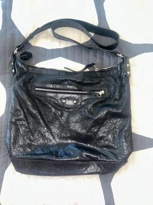 Balenciaga totebag - Svart äkta Balenciaga totebag väska med silver detalj. Köpt secondhand för cirka ett år sedan. Köpt för 8000, säljer för 7000. Mycket utrymme och bra om man ska ha mycket med sig. Väskan har inga defekter.