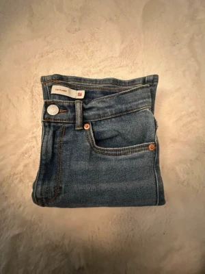 Blåa flare jeans från Levis - Snygga blåa jeans med flare-modell från Levis. Klassisk femficksdesign, normalhög midja och kontrastsömmar. Jeansen är i ett mjukt denimtyg och har en knappstängning framtill. Perfekta för en trendig och avslappnad stil.
