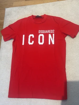 Dsquared2 ICON T-Shirt Red - Säljer en äkta Dsquared2 ICON T-shirt i rött med vit ICON-logga framtill.  T-shirten är i mycket fint skick och har endast använts cirka 6–7 gånger. Inga hål, fläckar eller andra anmärkningar. Kvitto finns som bevis på äkthet.  ✔️ 100 % äkta Dsquared2 ✔️ Kvitto finns ✔️ Storlek S ✔️ Tillverkad i Italien ✔️ Mycket fint skick ✔️ Endast använd ett fåtal gånger  Säljes då den inte används längre. Skickas snabbt efter köp.