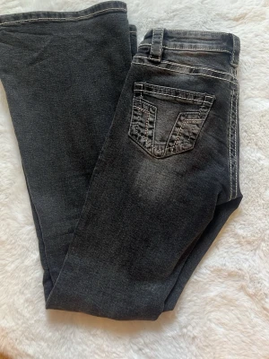 Svarta gina tricot 14+ jeans - Snygga svarta jeans med markerade vita sömmar och slitningar på framsidan. Klassisk femficksmodell med cool detalj på bakfickan. Jeansen har normal midja och bootcut ben. Fåtal stenar på fickorna har ramlat av men inget som syns i helhet💕 Säljer pågrund av lite korta i benen💕