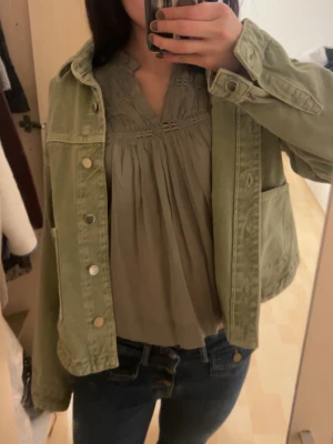 Ljusgrön oversized jeansjacka - Säljer en ljusgrön jeansjacka i oversized modell med stora fickor framtill och klassisk krage. Jackan har tryckknappar och avslappnad passform, perfekt för en chill och trendig look. Passar till det mesta och ger en cool vibe till outfiten.