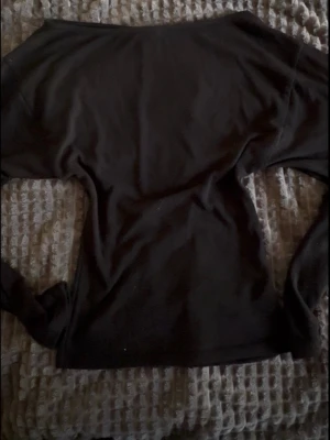 Svart långärmad topp med båtringning - En svart långärmad topp med båtringning och smal passform. Toppen är enkel och stilren, perfekt att matcha med jeans eller kjol. Den blir också lite mindre i midjan!
