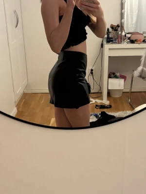 Svart kort kjol i skinnimitation - Snygg svart kort kjol i skinnimitation. Den är i barnstorlek men passar mig som brukar ha XS i underdelar💕pris kan diskuteras 