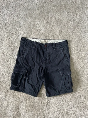 Mörkblåa Hollister Y2K Vintage Cargoshorts Shorts Storlek W36 - Mycket fina Hollister shorts i blå färg. | Jeansen är i mycket bra skick och sparsamt använda. |  Äkta som allt annat jag säljer! ✅ |  Storlek: W36 | Skick: Mycket Bra Skick | Färg: Blå | Märke: Hollister | Modell: Jeans |   Hör gärna av dig vid frågor så svarar jag så fort jag kan! 😁 |  (SKU - 160)