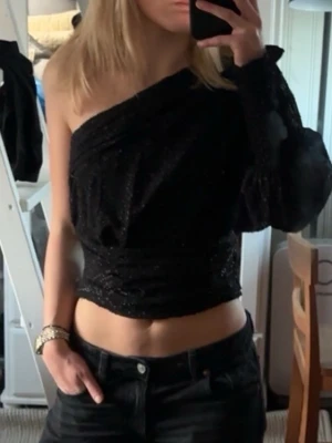 Oneshoulder topp från MNG - Säljer en svart glittrig oneshoulder topp från MNG i storlek M. Snyggt med både jeans o kjol. Använd endasr fåtal gånger! Skulle säga att storleken är mellan XS-M! 