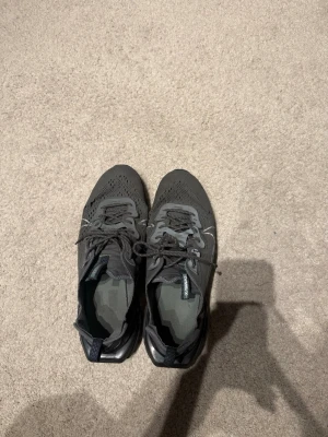 Mörkgrå sneakers med meshdetaljer - Snygga mörkgrå sneakers med ventilerande mesh på ovandelen och robust sula för extra grepp. Skorna har snörning och diskreta detaljer i olika grå nyanser. Perfekta för dig som gillar en sportig och clean stil. Ifrån Nike 