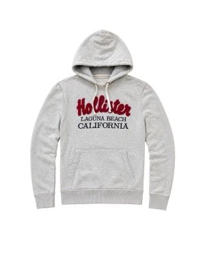 Grå Hollister hoodie - Säljer en ljusgrå hoodie från Hollister med stor broderad röd logga och texten 'Laguna Beach California' på bröstet. Hoodien har huva med vita snören och en klassisk magficka. Perfekt för chill dagar och streetwear-stil.