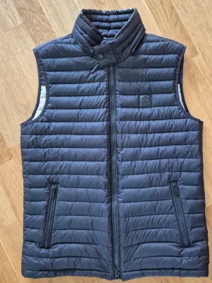 Moose Knuckles dunväst stl M - Snygg svart dunväst från moose knuckles med quiltad design och hög krage. 