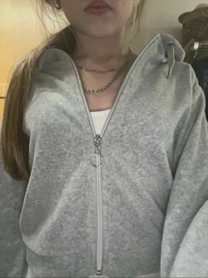 Grå zip hoodie med huva - Säljer en ljusgrå hoodie med dragkedja och huva. Hoodien har breda ärmar, ribbade muddar och en avslappnad passform. Perfekt till lager på lager och enkel att matcha med allt. Materialet känns mjukt och bekvämt, troligen bomullsblandning. Inga synliga loggor eller tryck.