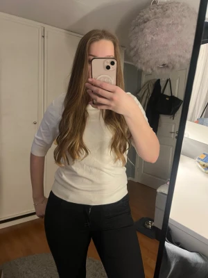 Vit ribbad topp med korta ärmar - Snygg vit topp med ribbad struktur och korta ärmar. Enkel och stilren design som passar perfekt till jeans eller kjol. Rund halsringning och normal passform, tillverkad i mjukt material som känns skönt mot huden.