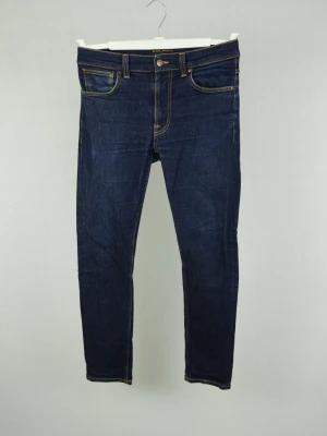 Nudie Jeans  - NUDIE JEANS Storlek : 32/30 Modell : Lean Dean Mått : A = 40CM - B = 98CM Användning : Jeansen är i ett fint skick utan defekter Nypris : Cirka 2000SEK Modellen på bilden : 182CM och väger 78KG