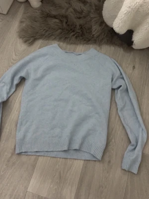 Ljusblå stickad tröja - Mysig ljusblå stickad tröja från Vero Moda. Tröjan har rund halsringning, långa ärmar och ribbade muddar vid ärmslut och nederkant. Perfekt för lager på lager och enkel att matcha med jeans eller kjol.