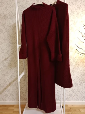 Vinröd stickad långklänning - Elegant och bekväm lång stickad klänning i mjuk akryl. Klänningen har en matchande stickad underkjol som ger ett fint fall och extra komfort. Perfekt både till vardag och mer uppklädda tillfällen beroende på hur du stylar den. Skön, varm och följsam. Tidlös design som aldrig går ur stil. Tillverkad i Turkiet. Finns i tre färger: beige, brun och vinröd