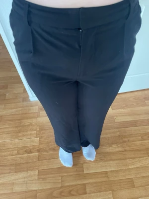 Svarta raka kostymbyxor - Snygga svarta kostymbyxor med rak passform och hög midja. Byxorna har diskreta fickor fram och stängs med knapp och dragkedja. Perfekta för en clean och stilren look. Materialet känns mjukt och följsamt. Aldrig använda, ändast testade! Ny pris 400kr. Tveka inte på att höra av dig om du har några frågor💕svarar snabbt, pris kan diskuteras!