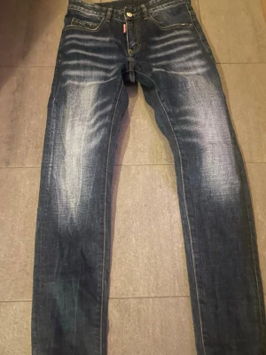 Mörkblå jeans från DSQUARED2 - Säljer mina blåa DSQUARED2 jeans då dom var för stora för mig. 101.5cm är jeanslängden, 24,5cm innerbenslängd. Midjan 72cm. Skulle säga att den passar mellan 163cm till 170cm.