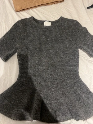 Grå peplumstickad topp från H&M - Säljer en grå stickad topp från H&M med peplumformad nederdel och korta ärmar. Aldrig använt och prislappen är fortfarande på💞 Köpt för 229 och säljer för 170