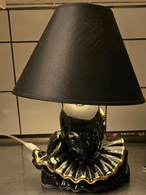 Bordslampa , Clown  retro 80 tal - Unik bordslampa med svart lampskärm och fot i form av en clownbyst i svart keramik med gulddetaljer. Lampan har en klassisk konformad skärm och dekorativ krage med guldkant. 80 tal, höjd med skärm 43 cm