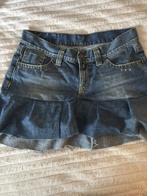 Jeanskjol med volang från Peak Performance - Säljer en snygg jeanskjol från Peak Performance med volangkant nedtill. Perfekt för dig som gillar denim och vill ha en trendig kjol i garderoben.