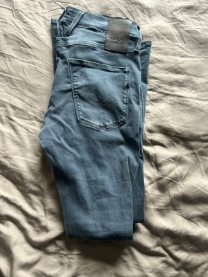Replay jeans - Säljer ett par blå jeans från Replay Hyperflex med klassisk femficksdesign och normal passform. Jeansen har en snygg tvättad look och är tillverkade i stretchigt jeansmaterial för extra komfort. Perfekta till din vardagsstil!