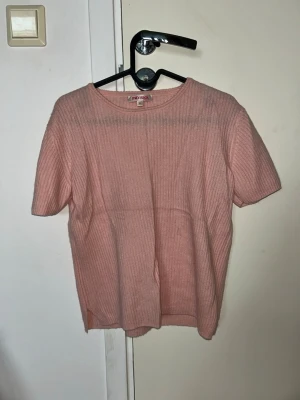 Rosa ribbad topp från Indiska - Söt ljusrosa ribbad topp från Indiska med rund halsringning och korta ärmar. Perfekt till jeans eller kjol för en enkel och fräsch look. Materialet känns mjukt och bekvämt mot huden. Skulle säga att det är S/M