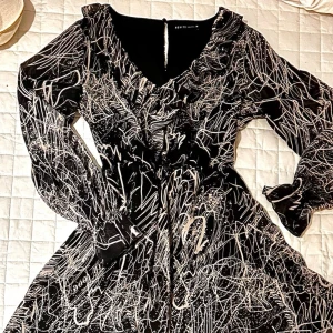 Mönstrad chiffongklänning från Mohito 🖤 - Säljer svartvita klänning från Mohito i storlek 38. Perfekt material i chiffong med snyggt abstrakt/grafiskt mönster, v-ringad med volanger & jättefina transparenta ärmar! Ärmarna har jättesnygg resår/smock vid handlederna & klockar ut sig i en volang. Klänningen har ett svart innerfoder så kroppen är inte genomskinlig. Sparsamt använd så i toppenskick bara att tvättlappen är bortklippt.  * Längd: ca 92cm * Axelbredd: ca 38cm * Midja: ca 35cm (resår) * Ärmlängd: ca 64cm