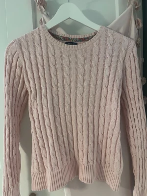 Ralph Lauren ljusrosa kabelstickad tröja  - Supersnygg ljusrosa kabelstickad tröja från Polo Ralph Lauren. Klassisk rund halsringning och ribbade muddar vid ärmslut och nederkant. Jättegullig och perfekt till sommaren. Perfekt för dig som gillar en tidlös och fräsch look med en feminin touch. Det står storlek L 12-14, vilket motsvarar ungefär storlek S!💗💗