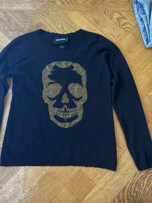 Svart zadig voltaire tröja  - Cool zadigtröja med guldig dödskalle som jag tyvärr inte får användning av. Den är i fint skick förutom en fläck på kragen som syns på sista bilden som antagligen går att tvätta bort! 