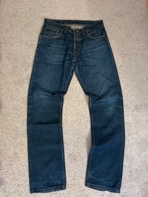 Nudie Jeans ”Even Steven” - Säljer ett par mörkblå vintage jeans från Nudie Jeans med klassisk rak passform. Modellen är ”Even Steven”. Storlek W33L34