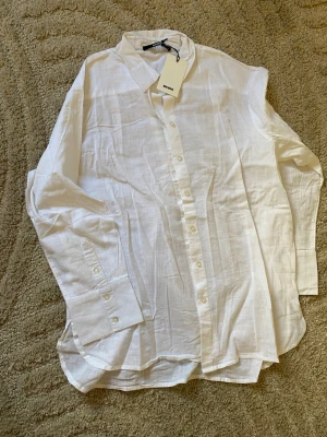 Vit linneskjorta från Bik Bok passar utmärkt till M och S - Klassisk vit skjorta från Bik Bok i luftigt linne. Skjortan har lång ärm, knappar framtill och en avslappnad passform. Perfekt till både jeans och kjol för en clean och fräsch look.