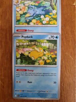 Pokémonkort Psyduck och Golduck - Två samlarkort från Pokémon TCG med motiven Psyduck och Golduck. Kortens design är färgglad med blå, gul och grön bakgrund och detaljerade illustrationer av karaktärerna i naturmiljö. Kort i standardformat, tryckta på klassiskt glansigt pappmaterial.