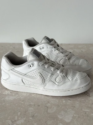 Nike Son Of Force Low | EU 38  - Klassiska vita Nike sneakers i lågt snitt med perforerade detaljer för extra ventilation. Skorna har en tydlig Swoosh-logga på sidan, vita skosnören och en vadderad plös. Tillverkade i läder med textilfoder för skön komfort.