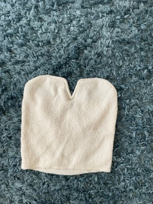 Beige bandeau tubtopp  - Säljer en beige bandeau tubtopp. Toppen är ärmlös och har en mjuk, lite texturerad yta. Perfekt att styla till jeans eller kjol för en trendig look.