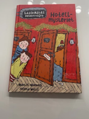 LasseMajas Detektivbyrå: Hotellmysteriet - En färgstark och illustrerad barnbok i serien LasseMajas Detektivbyrå, skriven av Martin Widmark och illustrerad av Helena Willis.  Perfekt för unga deckarfans. Har tidigare skrivit mitt namn på första sidan men har suddat bort det, finns lite spår dock.