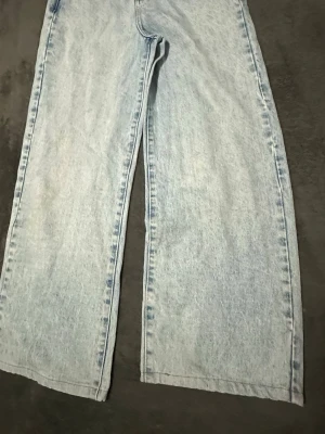 Ljusblå wide leg jeans från NA-KD - Säljer ett par ljusblå jeans från NA-KD med breda ben och hög midja. Jeansen har klassisk femficksdesign och är tillverkade i denim. Perfekta för en avslappnad och trendig look.