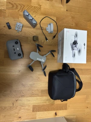 DJI Mini 4k Fly more combo - DJI Mini 4k drönare med tillbehör som fjärrkontroll, batterier, laddare, propellrar, väska och originalkartong. Drönaren är kompakt och lätt, i ljusgrå plast med svart kamera framtill. Perfekt för dig som vill filma och fota från luften.