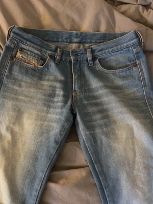 Ljusblå bootcut jeans från Diesel - Säljer ett par ljusblå lågmidjade bootcut jeans från Diesel med snygg tvätt och klassisk femficksmodell. Köpta på sellpy men var tyvärr för små och glömde lämna tillbaka. Innerbenslängd: 76cm Midjemått rakt över: 38cm Pris kan diskuteras