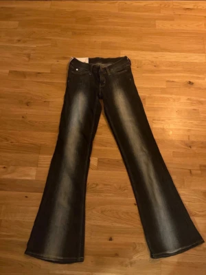 Svarta utsvängda jeans Cheap Monday - Snygga svarta jeans från Cheap Monday med utsvängda ben och slitningar längs framsidan. Jeansen har klassisk femficksdesign och en cool logga på bakfickan. Perfekta för dig som gillar retrostil och vill sticka ut.