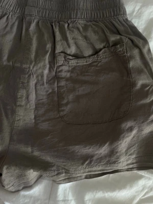 Beige shorts med resårmidja - Säljer sköna somriga linneshorts i storlek XS men funka helt med större storlek också. Färgen är en brunaktig färg 