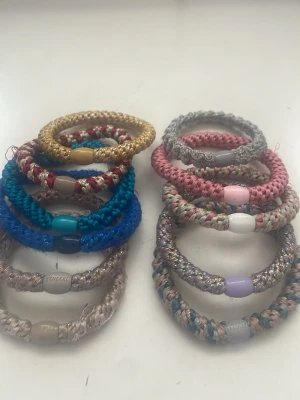 Färgglada kknekkis - Säljer ett set med spiralformade hårsnoddar i olika färger som guld, blå, rosa, silver och beige. De är gjorda av glansigt, flätat material och har plastdetaljer i mitten. Perfekta för att ge en färgklick till din frisyr och hålla håret på plats. 15kr styck