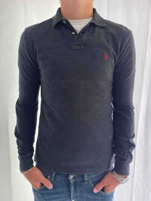 Ralph Lauren långärmad piké  - Tjena! Långärmad Piké från Ralph Lauren Svart grå| storlek S | skick 10/10 | modell 185cm 76kg | märke Ralph Lauren | denna långärmade piké är perfekt till ett par shorts eller jeans från min profil, hör av dig vid frågor eller funderingar😁 //Gradioso