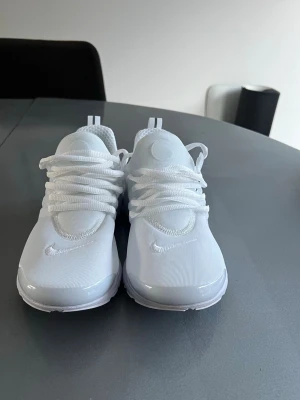 Helvita sneakers med mesh och tyg - Säljer ett par helvita sneakers med stilren design. Skorna har ovandel i mesh och tyg, tjocka vita skosnören och en chunky sula. Perfekta för dig som gillar en clean look och vill ha något som passar till allt. Säljer på grund av för små!