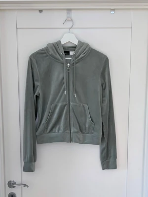 Grön velourhoodie med dragkedja - Mjuk grön hoodie i velour från Gina Tricot med dragkedja framtill, huva med dragsko och två stora fickor. Perfekt för en chill och avslappnad stil. Långa ärmar och ribbade muddar ger en skön passform.
