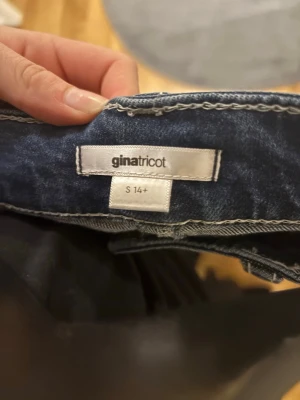 Bootcut jeans från Gina Tricot - Snygga mörkblå bootcut jeans från Gina Tricot med coola detaljer på bakfickorna. Jeansen har en klassisk femficksdesign och är tillverkade i denim med stretch för extra komfort. Perfekt för dig som gillar en trendig och bekväm stil.