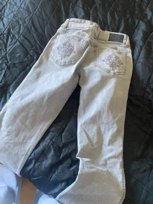 Grå jeans med broderade bakfickor - Säljer ett par grå jeans från 157 med snygga broderade detaljer på bakfickorna. Jeansen har klassisk femficksdesign och raka ben. Perfekt för dig som vill ha en cool och stilren look.