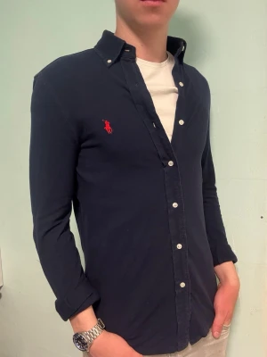 Marinblå Ralph Lauren skjorta –  S - Säljer denna stilrena och snygga marinblåa Ralph Lauren skjorta. Skjortan är i mycket bra skick. Storlek S. Är i skönt piké-material.  Har du några frågor? Tveka inte att höra av dig. Allt gott från Deluxe garderoben ⭐️