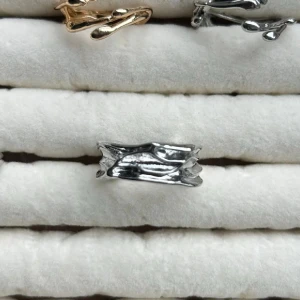 Silvrig ring med organisk form - Unik silvrig ring med en organisk, grenliknande design som ger en cool och modern känsla. Ringen har en bred form och blanka ytor som reflekterar ljuset snyggt. Perfekt för dig som gillar statement-smycken med naturinspirerad look.