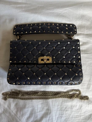 Valentino väska  - Säljer min super fina medium nappa rockstud spike bag från valentino. Den har ett bränn märke på baksidan av väskan (sista bilden) men utöver det så är väskan i super fint skick. Köpte den för 5 år sen för 20 000kr, nypris nu är 30 000kr.