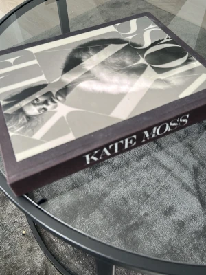 Kate Moss fotobok - Säljer en snygg fotobok med svartvitt omslag och texten 'KATE MOSS' på ryggen. Boken har hårda pärmar och är fylld med ikoniska bilder och modeinspiration. Perfekt för dig som gillar mode, fotografi och stil.