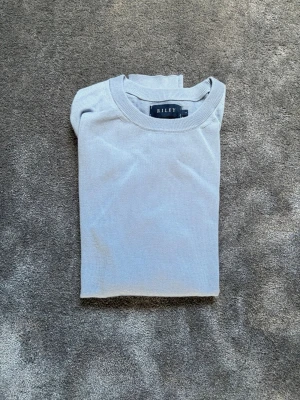 Ljusblå tröja från Riley - Ljusblå, tunn och mjuk tröja från Riley med rund halsringning och långa ärmar. Tröjan har en enkel design utan mönster och ribbade muddar vid ärmslut och nederkant. Perfekt för lager-på-lager och snygg till jeans.